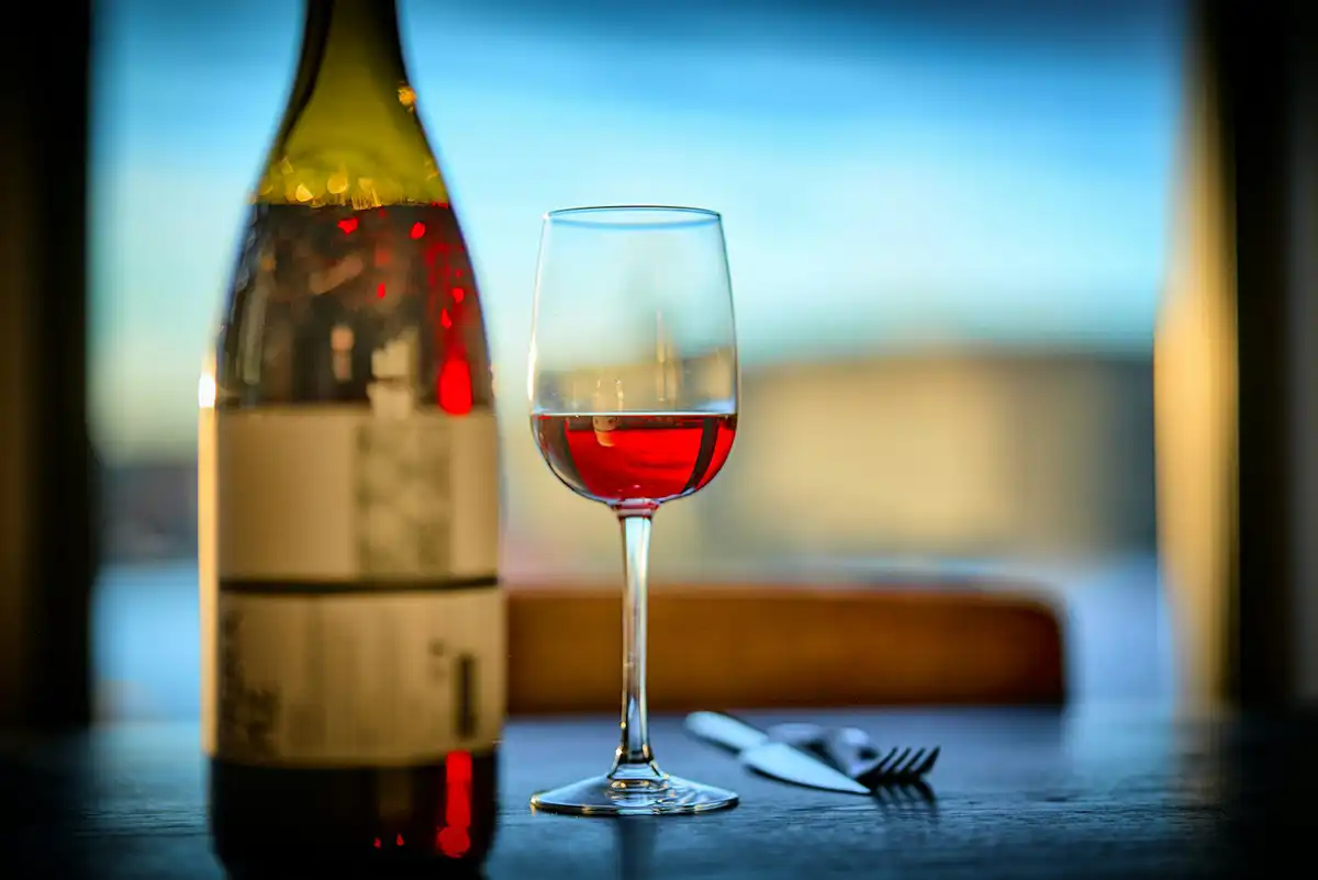 A wine bottle and a wine glass next to each other on a restaurant table